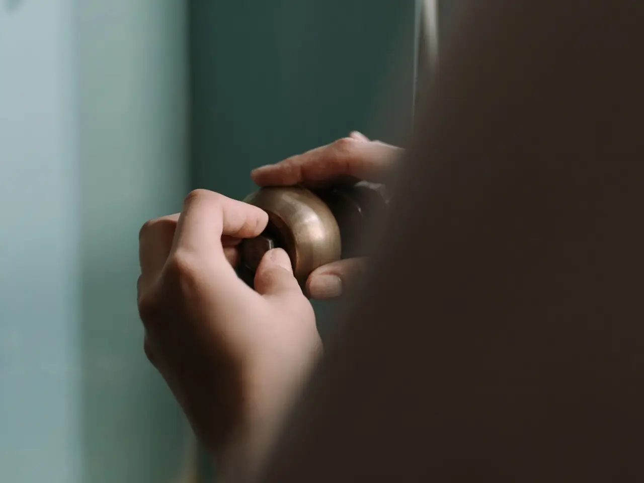 Hands tightening a pipe fitting under a kitchen sink